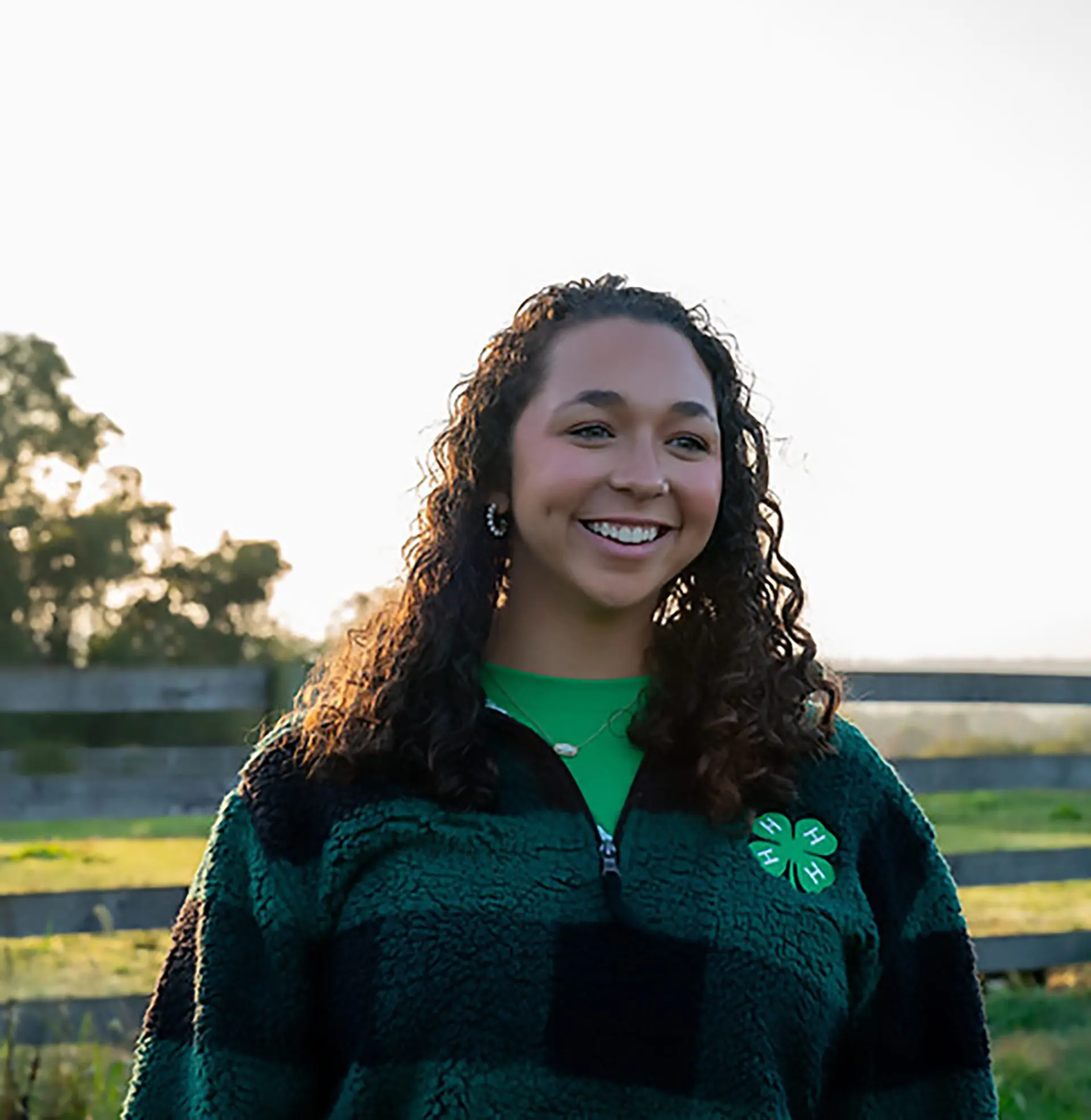woman with curly hair in front of fence